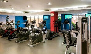 Un gimnasio con diferentes máquinas de cardio, una cinta de correr y una máquina de remo.