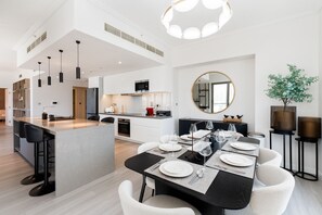 Een moderne keuken met witte kasten, een centraal eiland en hangende lampen.