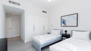 Et moderne hotelværelse med to senge, et garderobeskab, et skrivebord og et billede på væggen.