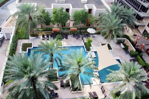 Un área de piscina en la azotea con palmeras, sillones de descanso y una piscina.