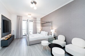 Een moderne hotelkamer met een groot bed, een televisie, een bureau en een zithoek.