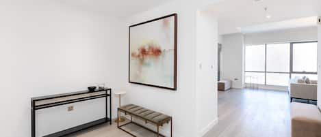 A modern living room with a console table, bench, and a large abstract painting.