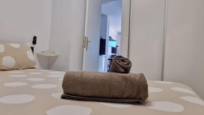 A neatly made bed with a rolled towel, a bedside lamp, and a polka dot pillow. - LAS VISTAS 1 BEDROOM WIFI FREE (Los Cristianos)