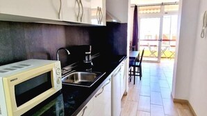 A compact kitchen with a microwave, sink, and cabinets. - LAS VISTAS 1 BEDROOM WIFI FREE (Los Cristianos)