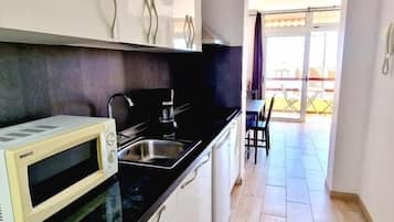 Een koelkast, een magnetron, kookgerei, borden en bestek