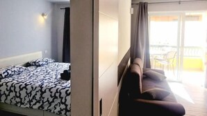 Ein Hotelzimmer mit einem Bett, einem Sofa und einem Balkon mit Stühlen.