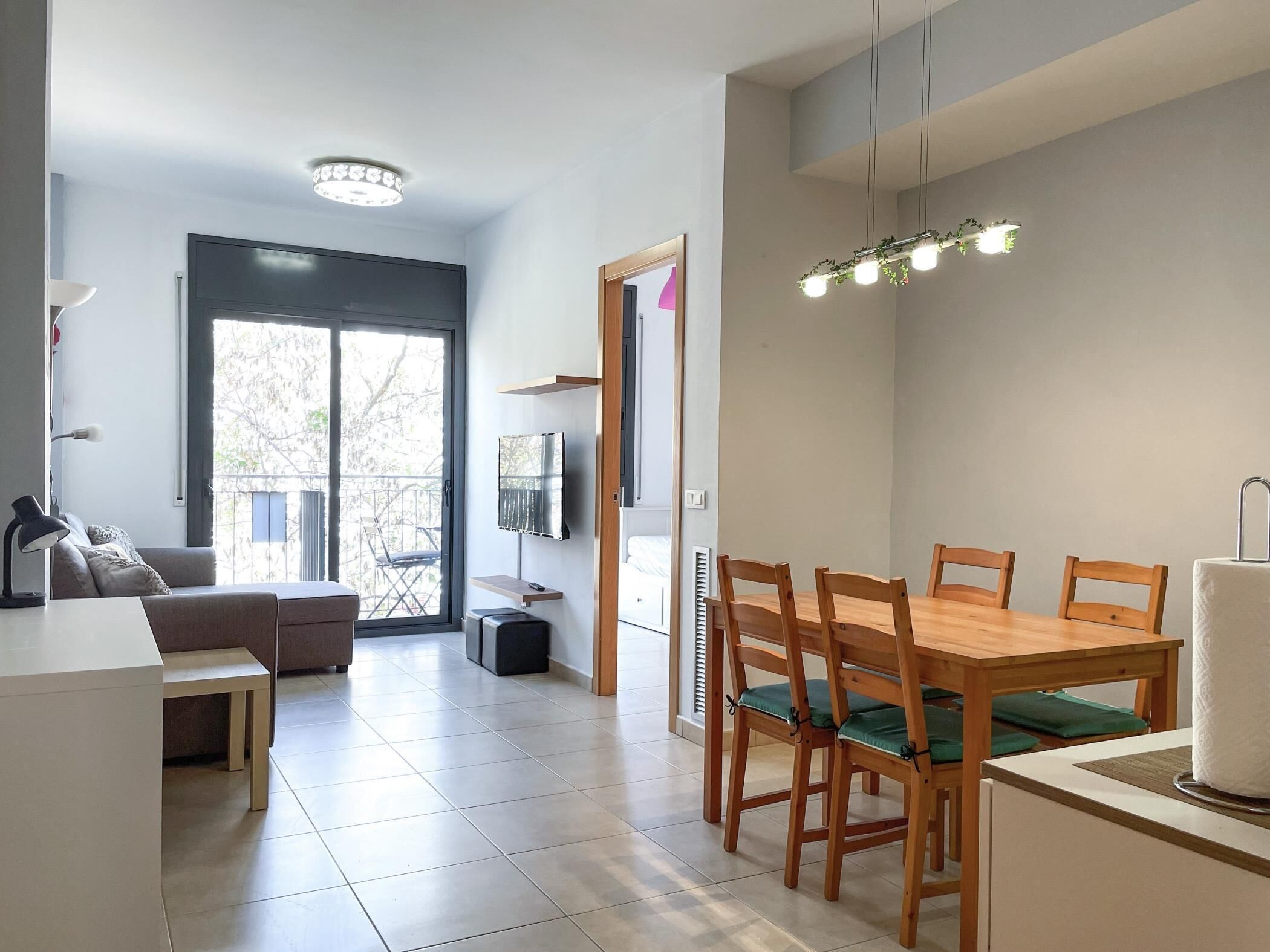 Un espace de vie moderne comprenant un coin repas, un canapé, un téléviseur et un balcon.