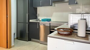 A modern kitchen with dark cabinets, stainless steel appliances, and a white countertop.