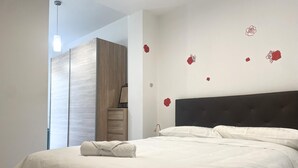 A neatly made bed with white linens, a dark headboard, and a wooden wardrobe in the background.
