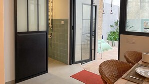 Interior moderno com porta de vidro deslizante para uma varanda com mobiliário e plantas.
