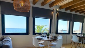 A dining area with a view of the sea, a wooden ceiling, and a large mirror reflecting the room.