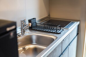 Una cocina moderna con un lavamanos de acero inoxidable, un escurreplatos negro y un horno empotrado.