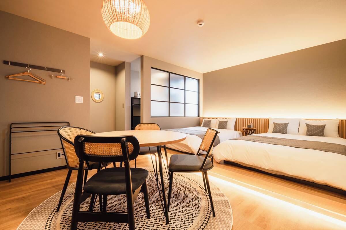 Quarto moderno com cama, mesa de cabeceira e um espaço de refeições com cadeiras e mesa.