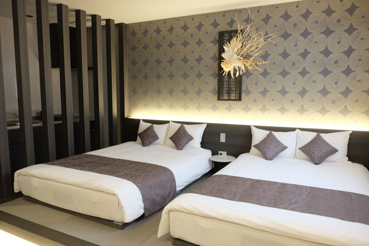 A hotel room with two beds, a nightstand, a decorative wall piece, and a patterned wall.