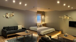 A modern hotel room with a sofa, a bed, a coffee table, and a TV. - BEPPU non (Beppu)