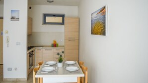 A modern kitchen with wooden cabinets, a dining table set with plates and glasses, and a framed picture on the wall.