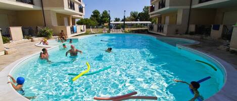 Una piscina rodeada por un edificio de varios pisos con balcones.