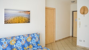Un couloir avec une porte en bois, un téléphone fixé au mur et un luminaire au plafond.