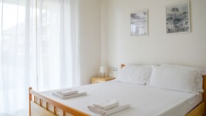 Un lit bien fait, avec du linge de lit blanc, une tête de lit en bois et une table de chevet avec une lampe.