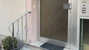 A building entrance with a metal staircase, a door with a textured screen, and a security camera on the wall. - Ahr valley heart (Bad Neuenahr-Ahrweiler)