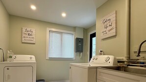 Un cuarto de lavado con dos lavadoras, un lavamanos y una ventana con persianas.