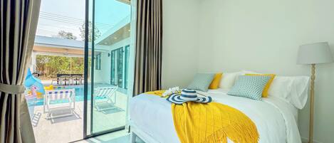 A hotel room with a bed, a lamp, and a view of a pool area.