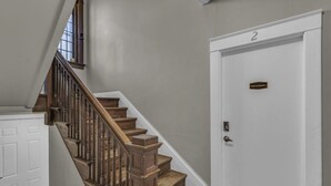 Una escalera con escalones de madera y una puerta blanca con el número 2.