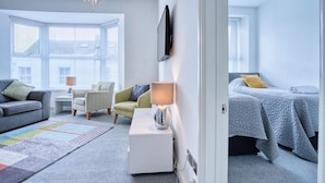 A modern bedroom with a bed, a sofa, a chair, and a TV.