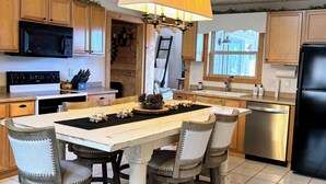 A kitchen with wooden cabinets, a stainless steel refrigerator, a microwave, and a dining table with chairs.