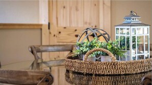 A dining table with a glass top, surrounded by wooden chairs, a woven basket with greenery, and a white lantern with a metal top. - Mountain Views/Fire Pit/Hot Tub/Game Room/Close 2 Strip (Sevierville)