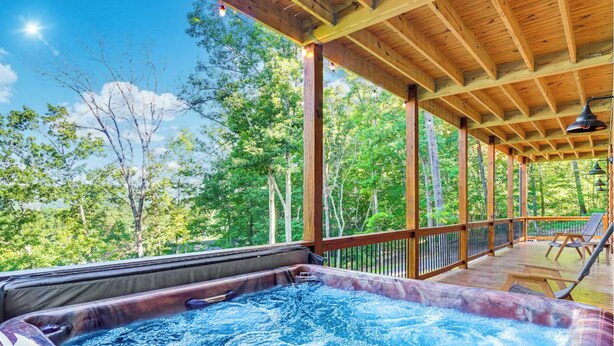 A hot tub under a wooden deck with a view of a forest. - Mountain Views/Fire Pit/Hot Tub/Game Room/Close 2 Strip (Sevierville)