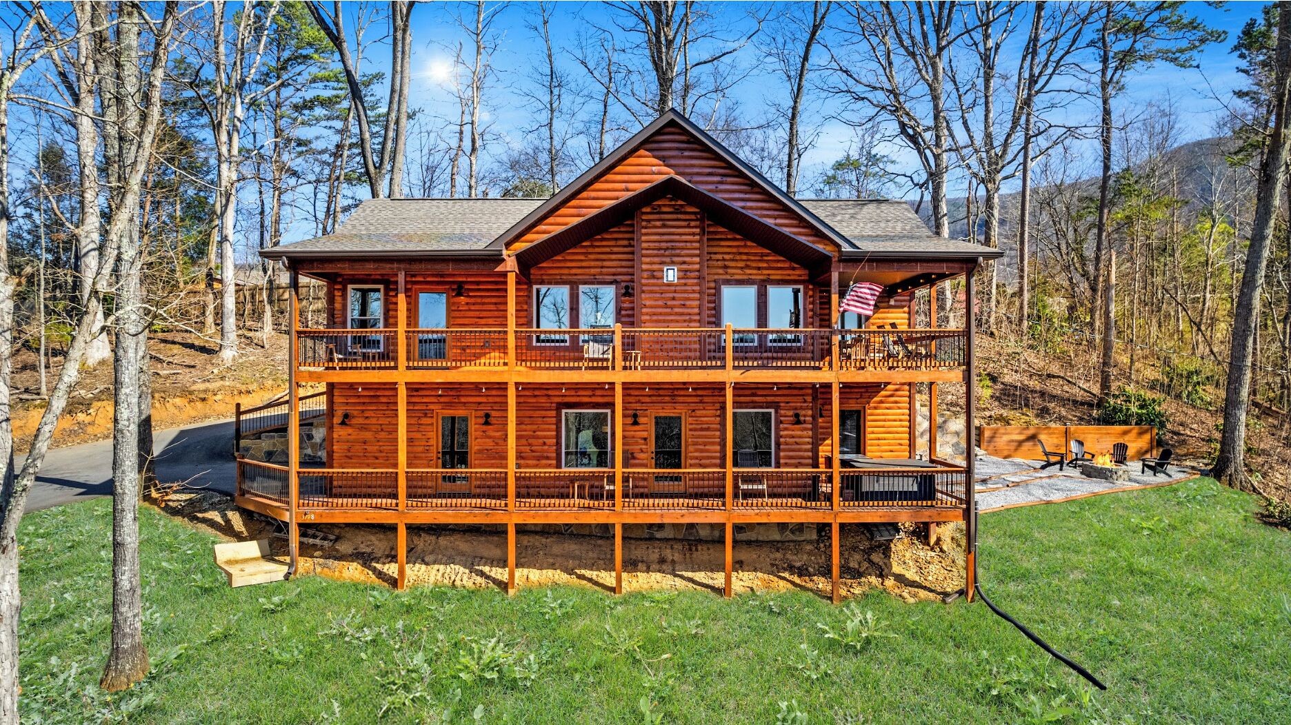 Une cabane en rondins à deux étages, dotée d’un balcon, entourée d’arbres et surplombant un ciel dégagé.
