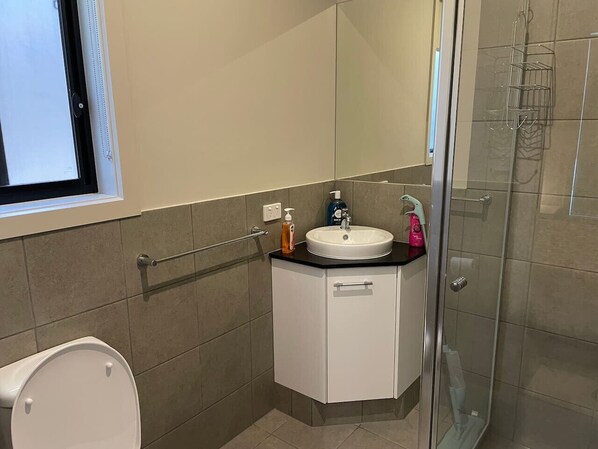 A modern bathroom with a toilet, sink, and shower.