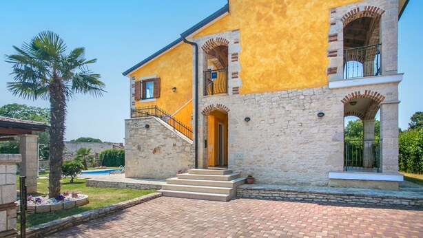 A two-story building with a yellow facade, stone base, and a central entrance with steps. - Villa Nevena by Interhome (Poreč)