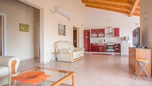 A spacious living area with a glass coffee table, a beige sofa, and a kitchen in the background. - Villa Nevena by Interhome (Poreč)
