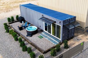 A compact, modern RV-style building with a blue roof, a hot tub, and a barbecue area. - Dark Sky Container Near Sedona • Hot Tub & Desert Views (Cornville)