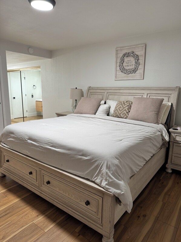 Une chambre à coucher avec un lit en bois, une table de chevet, une lampe de chevet et un élément décoratif mural.