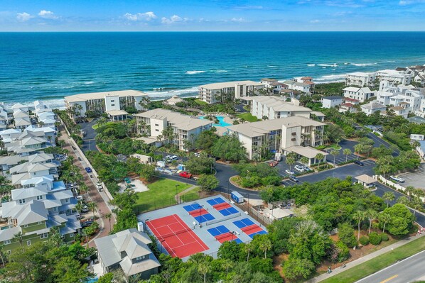 Zona residencial costera con propiedades frente al mar, cancha de tenis y aparcamiento.