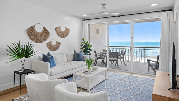 A modern living room with a white sofa, a coffee table, and a large window overlooking the ocean. - Gulf Front 2 Bedroom in High Pointe with Amazing Views - 35E (Inlet Beach)