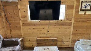 A cozy living room with a wooden TV stand, a coffee table, and two sofas. - Lodge in Big Stone MN (Graceville)