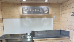A compact kitchen with a stainless steel countertop, a sink, and wooden walls. - Lodge in Big Stone MN (Graceville)