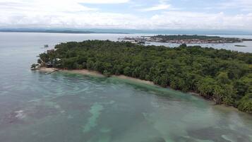 Vista aèria d'una illa tropical amb platja i una densa vegetació forestal.