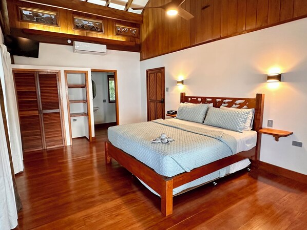Un dormitorio con una cama de madera, un armario de madera y un ventilador de techo.