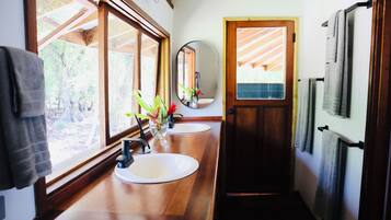 Un baño con mostradores de madera, dos lavamanos, un espejo y toallas colgadas en un perchero.