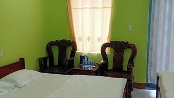 Ein Hotelzimmer mit zwei Betten, einem kleinen Tisch mit Wasserflaschen und einem Fenster mit Vorhängen.