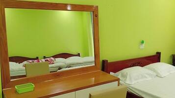 A room with a bed, a desk, and a chair. There is a painting on the wall above the bed.