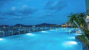 A rooftop infinity pool with a glass balustrade, surrounded by modern buildings and a mountain in the background. - MOTEL DONG KHOI (Phu Tan)