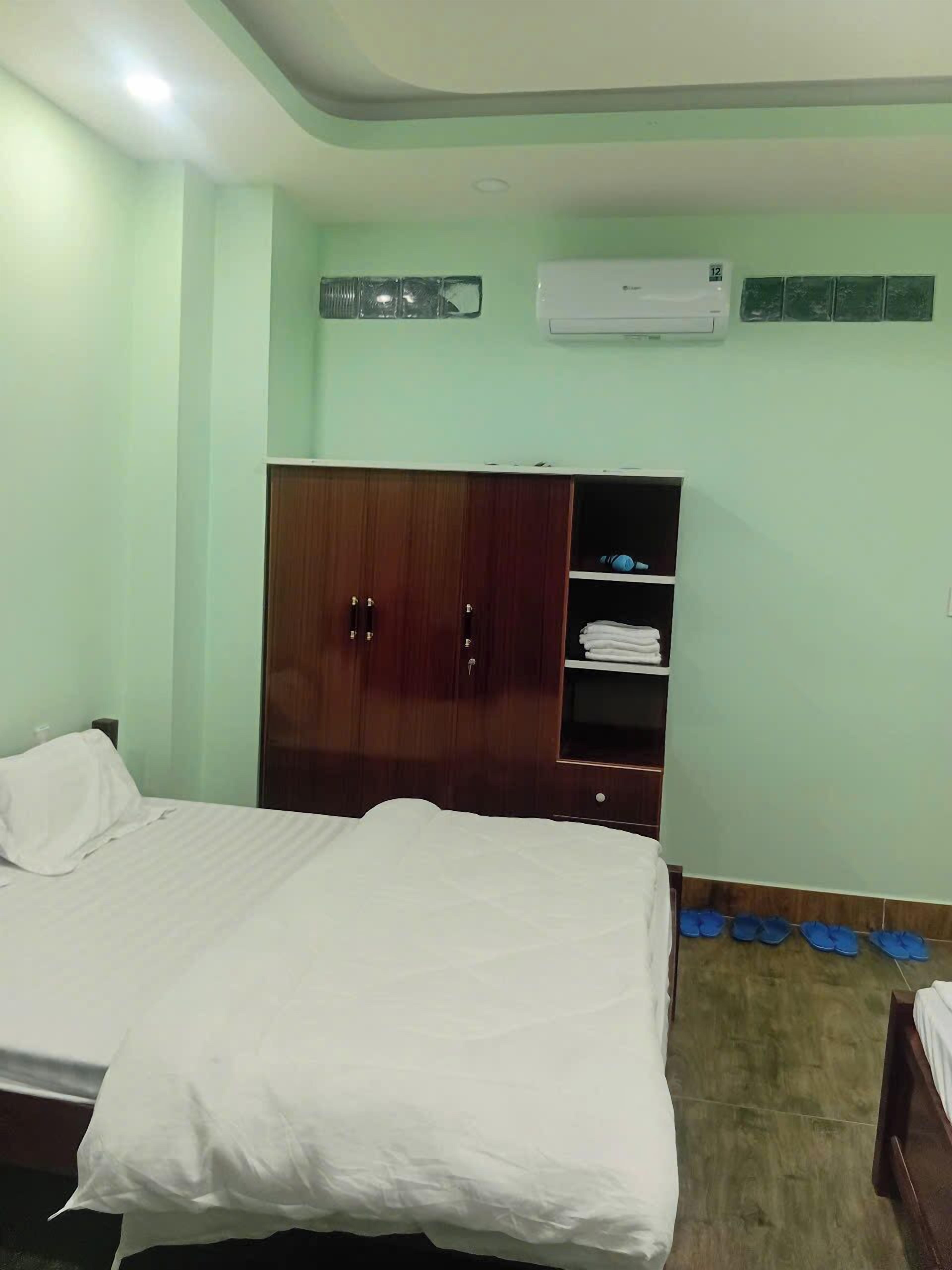 A hotel room with a bed, wardrobe, and air conditioning unit.
