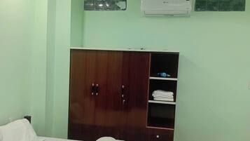 A hotel room with a bed, wardrobe, and air conditioning unit.