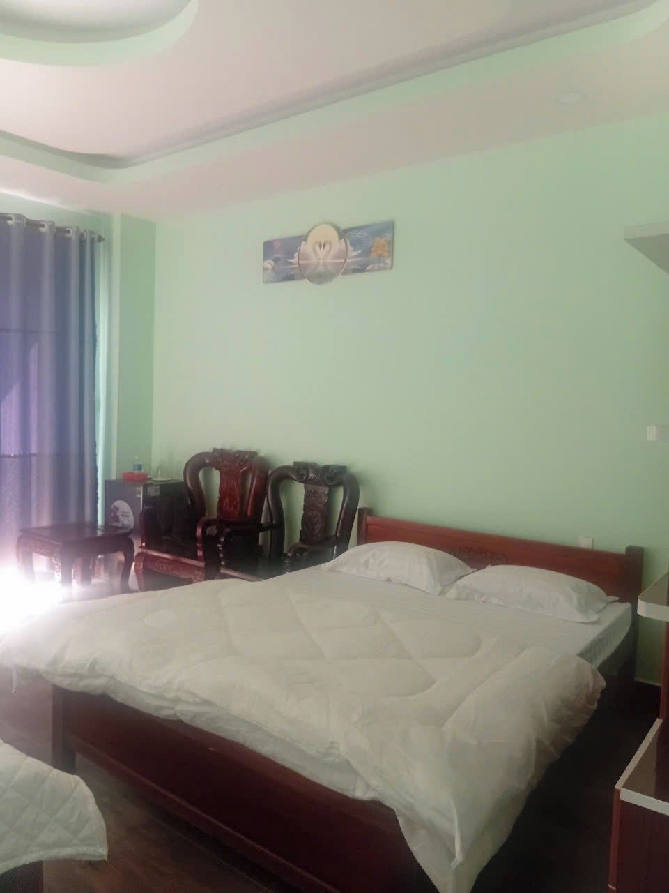 Una habitación de hotel con una cama grande, un cabecero de madera, un escritorio con una silla y un cuadro en la pared.